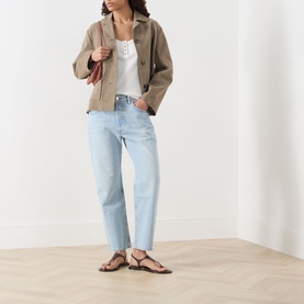 Model wearing Citizens of Humanity Winslow Boyfriend Jeans in Horizon light wash, styled with a beige jacket, white top and brown sandals.