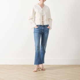 Model wearing Citizens of Humanity Goldie Ankle Kick Flare Jeans in Calla, mid-blue with raw hems, styled with a white broderie top and tan mules.