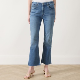 Model wearing Citizens of Humanity Goldie Ankle Kick Flare Jeans in Calla, mid-blue denim with raw hems and faded details, styled with strappy heeled