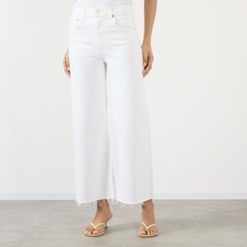 Model wearing Citizens of Humanity Lyra High-Rise Cropped Wide Leg Jeans in Soft White with frayed hem, styled with tan strappy sandals.