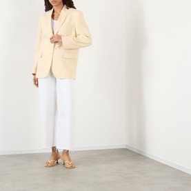 Model wearing Citizens of Humanity Lyra High-Rise Cropped Wide Leg Jeans in Soft White with frayed hem, styled with a cream blazer and tan heeled