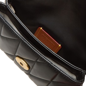 Coach black quilted leather crossbody bag interior detail, showing gold-tone turn-lock closure and structured compartment lining