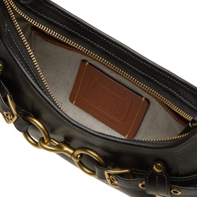Coach black leather shoulder bag interior view, gold-tone chain detailing and zip, beige lining with brown logo patch
