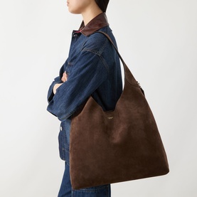 Model carrying Coach Brooklyn 39 Suede Shoulder Bag in Dark Chocolate, worn over shoulder, styled with denim jacket