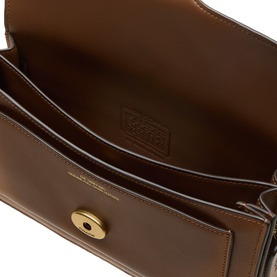 Coach dark brown leather shoulder bag interior view, showing smooth lining, debossed logo, and gold-tone twist-lock closure detail