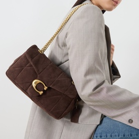 Model carrying Coach Tabby 26 Quilted Shoulder Bag in dark chocolate quilted suede with gold-tone chain strap and C-logo clasp