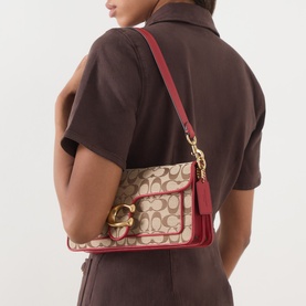 Model carrying Coach Tabby 26 Jacquard Shoulder Bag in Poppy Signature, red leather trim, gold-tone hardware, worn over shoulder
