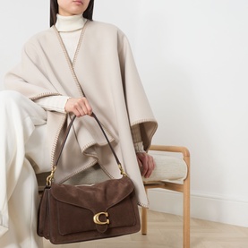 Model carrying Coach Tabby 36 Suede Shoulder Bag in Dark Chocolate with gold-tone hardware, styled with a cream wool cape and turtleneck