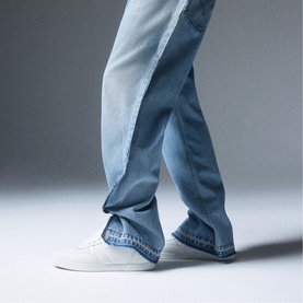 Model wearing Christian Louboutin white low-top trainers styled with light-wash blue jeans
