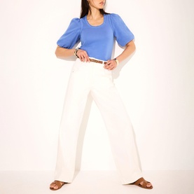 Model wearing Mint Velvet Blue Embellished Solid Top with scoop neck and puff sleeves, styled with wide-leg white trousers and tan sandals.