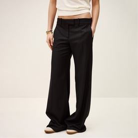 Model wearing Bash Womens French Dress trousers in blue, wide-leg tailored cut, styled with a white top and gold bracelet