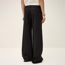 Model wearing Bash Womens French Dress wide-leg trousers in blue, shown from behind with a white top and gold bracelet.