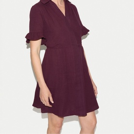 Model wearing Jigsaw purple mini shirt dress with V-neckline, flutter sleeves, and fitted waist in a wrap style