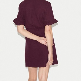 Model wearing Jigsaw purple mini dress with ruffle sleeves and tie waist, seen from the back