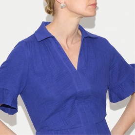 Model wearing Jigsaw blue short-sleeve wrap-style dress with collar neckline, styled with drop earrings