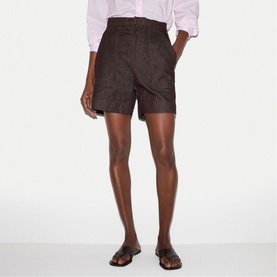 Model wearing dark brown high-waisted shorts with front pockets, styled with a light pink shirt and brown flat sandals