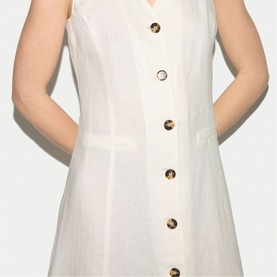 Model wearing Jigsaw cream sleeveless dress with tortoiseshell buttons and front patch pockets, close-up detail view