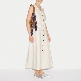 Model wearing Jigsaw cream sleeveless button-front midi dress, styled with a patterned tote bag and silver loafers.