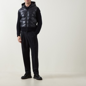 Model wearing Moncler navy cardigan with quilted gilet front, hood, and knit sleeves, styled with black tailored trousers and black shoes