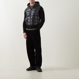 Model wearing Moncler black quilted down cardigan with hood, styled with black trousers and chunky trainers