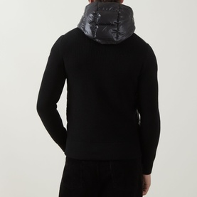 Model wearing Moncler black wool cardigan with quilted glossy polyester hood, seen from the back