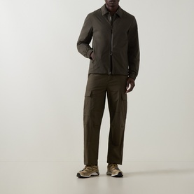 Model wearing Moncler Caramantran Down Overshirt in dark green with zip closure, styled with matching cargo trousers and trainers.