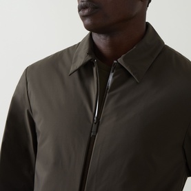 Model wearing Moncler Caramantran Down Overshirt in dark green, showing collar and zip closure detail, styled over a dark layer.