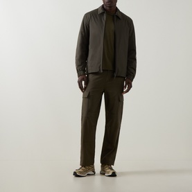 Model wearing Moncler Caramantran Down Overshirt in dark green with zip closure, styled with matching cargo trousers and trainers.
