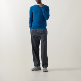 Model wearing Moncler navy cotton crew neck jumper, styled with dark grey trousers and grey trainers.
