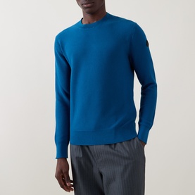 Model wearing Moncler navy cotton crew neck jumper with logo badge on sleeve, styled with grey pinstripe trousers