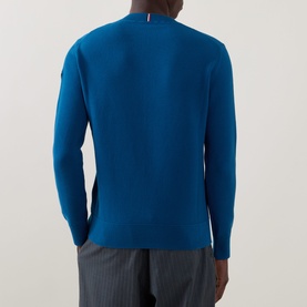 Model wearing Moncler navy cotton crew neck jumper, rear view, styled with grey trousers, small flag logo at back collar