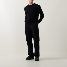 Model wearing black crew neck knit jumper with black cargo trousers and black chunky sole shoes