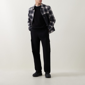 Model wearing grey and black plaid overshirt, black crewneck, black cargo trousers and black chunky trainers
