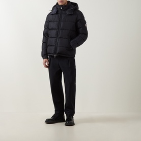 Model wearing Moncler navy down jacket with hood, styled with black trousers and black boots