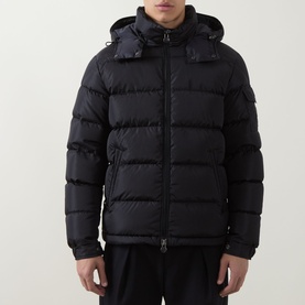 Model wearing Moncler navy down jacket with detachable hood, quilted panels and zip pockets, styled with black trousers.