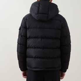 Model wearing Moncler navy down jacket, rear view, showing quilted panels, attached hood and arm badge detail