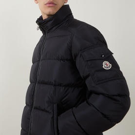 Model wearing Moncler navy down jacket with quilted body, funnel neck, zip fastening and logo badge on sleeve