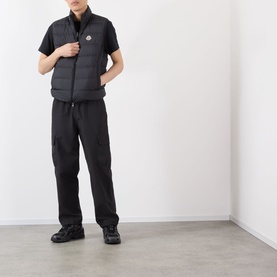 Model wearing Moncler Contrin Down Gilet in black, styled with black trousers and black trainers.