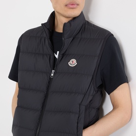 Model wearing Moncler Contrin Down Gilet in black, sleeveless padded design with stand collar, two-way zip and chest logo badge.