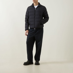 Model wearing Moncler navy quilted down jacket with zip fastening, styled with navy trousers and black chunky-sole shoes.