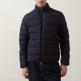 Model wearing Moncler navy quilted down jacket with funnel neck and zip fastening, styled with navy trousers.