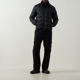 Model wearing Moncler black quilted down jacket with zip fastening, styled with black cargo trousers and dark shoes