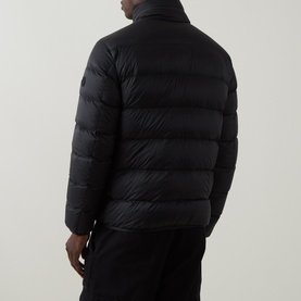 Model wearing Moncler black quilted down puffer jacket, rear view, styled with black trousers.