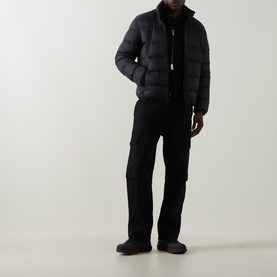 Model wearing Moncler black quilted down puffer jacket with stand collar, styled with black trousers and dark boots.