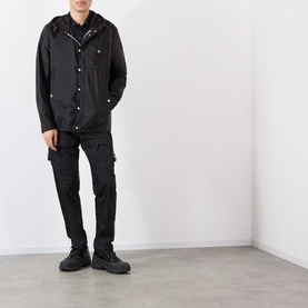 Model wearing Moncler black polyamide hooded jacket with press-stud front, styled with black cargo trousers and chunky black boots.