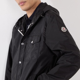 Model wearing Moncler black hooded jacket in polyamide, featuring chest pockets, silver snap buttons and logo arm patch