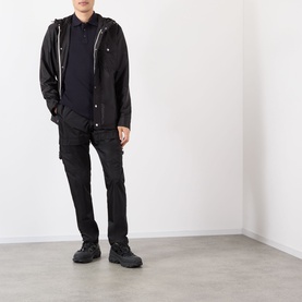 Model wearing Moncler black polyamide hooded jacket with zip details, styled with dark trousers and black boots.