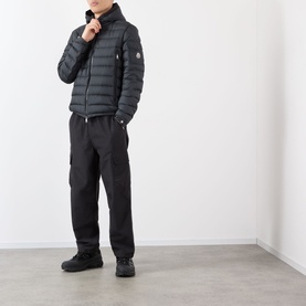 Model wearing Moncler Galion Short Down Jacket in black, quilted finish, full zip-through, logo badge on sleeve, styled with black cargo trousers and