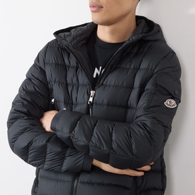 Model wearing Moncler Galion Short Down Jacket in black, quilted hooded style with sleeve logo badge, styled with black graphic T-shirt.