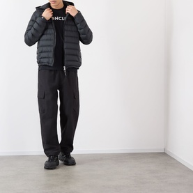 Model wearing Moncler Galion Short Down Jacket in black, quilted finish with hood, paired with black logo tee and black cargo trousers.